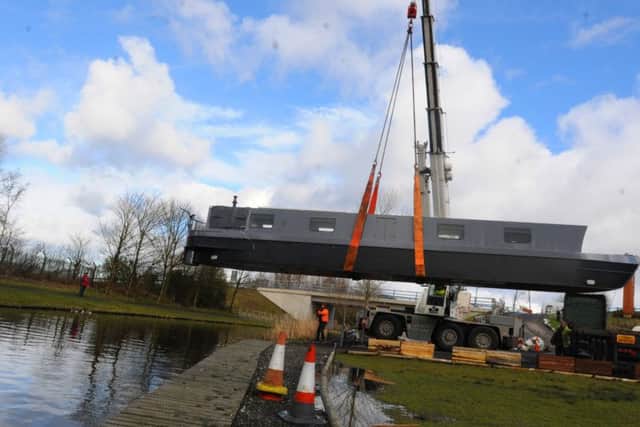 A canal boat, which will be a floating arts venue, Idle Women, is delivered on a lorry and lifted with a crane into the Leeds-Liverpool Canal.  It will tour the waterways until 2017.
