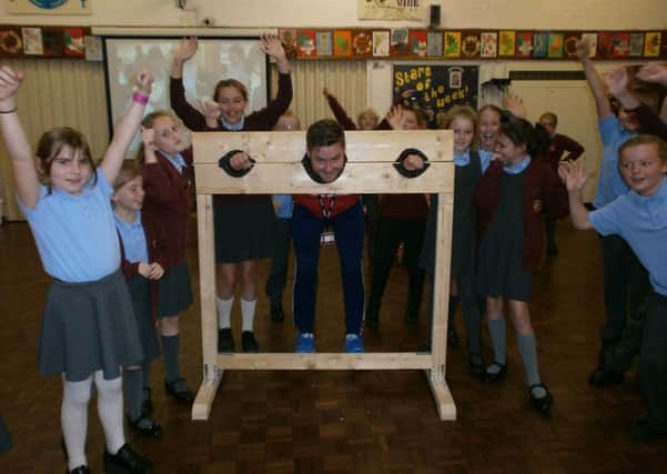 Mr Grimes takes his place in the stocks at Holy Trinity Primary School in Burnley in preparation for Children in Need. (s)