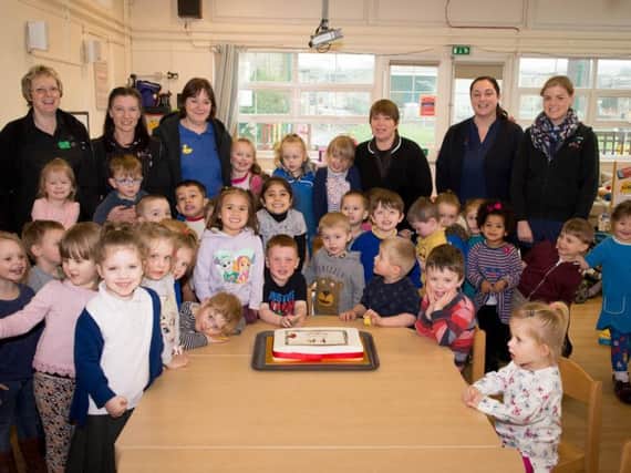 Staff and children at Taywood Nursery in Burnley celebrate its 85th anniversary with a cake
