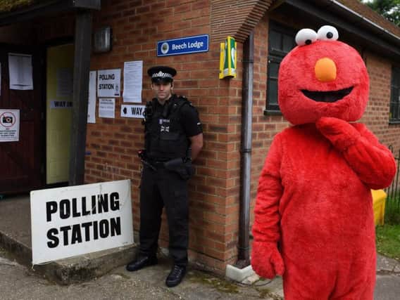 Police and a man dressed as Elmo outside a polling station in the village of Sonning, Berkshire