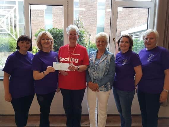 Yvonne Roberts presents the cheque to Mary Grange watched by other members of the Contempo Choir.