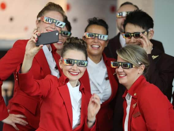 Virgin Atlantic Cabin Crew and Pilots take a selfie as they check their solar glasses on the ground at London's Heathrow airport ahead of their flight VS5 to Miami, USA, during which they are expected to fly through the area of totality of the solar eclipse