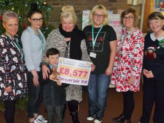 Elaine and her grandson Hugh present the cheque from the money raised at the masquerade ball to staff and day patients at Pendleside Hospice.