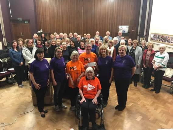 Burnley Contempo Choir co-ordinator Yvonne Roberts presents a cheque to Clive Forrester and representatives of the MS Society, watched by choir members.