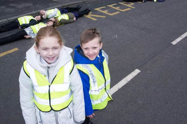 Pupils Alexandra Bishop and Olly Spencer, with other students lying on the road markings outside St Mary Magdalene's RC Primary School as part of their road safety campaign.