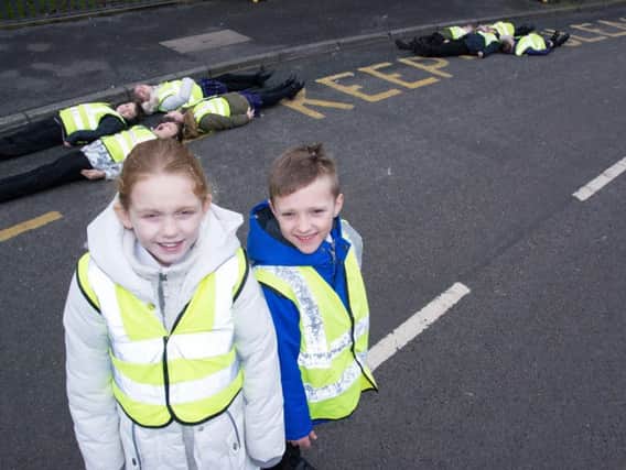Pupils Alexandra Bishop and Olly Spencer, with other students lying on the road markings outside St Mary Magdalene's RC Primary School as part of their road safety campaign.