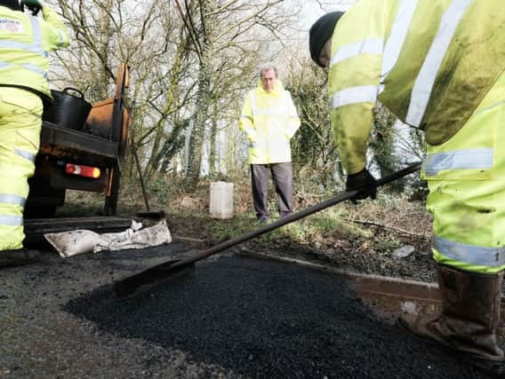 Cabinet member Coun Keith Iddon watches a pothole being repaired in Chipping recently.