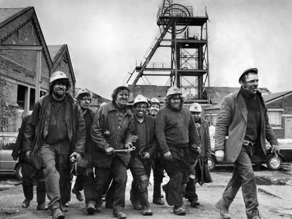 Hapton Valley miners  leaving the lamp room after collecting their lamps to go over to the surface drift.