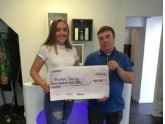 Molly hands over a cheque for 760 to Ethan's dad Andrew after  completing her haircut challenge.